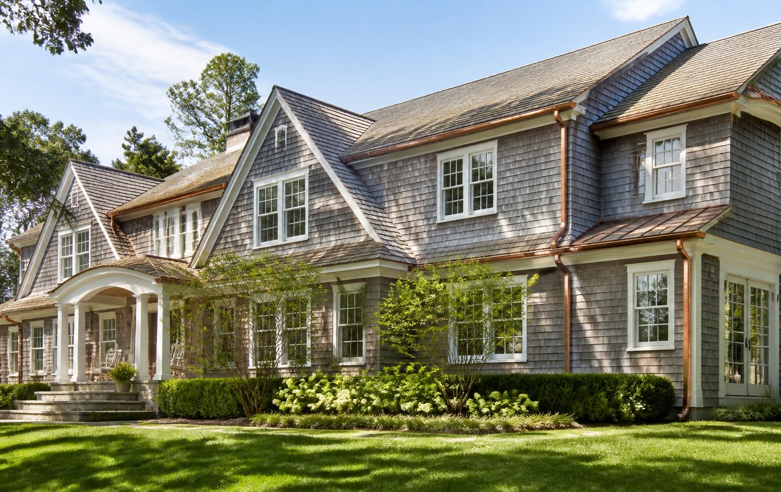 Classic shingle-style home with bright copper half-round gutters, matching downspouts, white trim and manicured Fairfield County landscaping