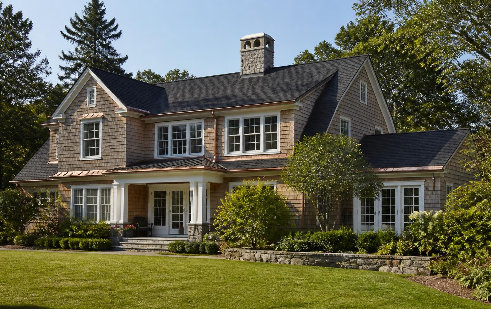 Traditional Greenwich-style shingle home with a brand new dark architectural shingle roof, copper flashing and a stone chimney under a clear blue sky